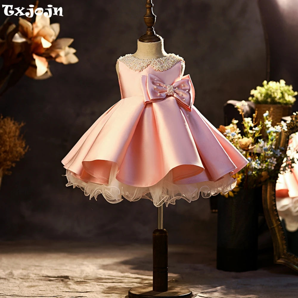 Pink satin princess gown for girls featuring glitter pearls and a bow, ideal for school performances and catwalk shows by Ansoff.