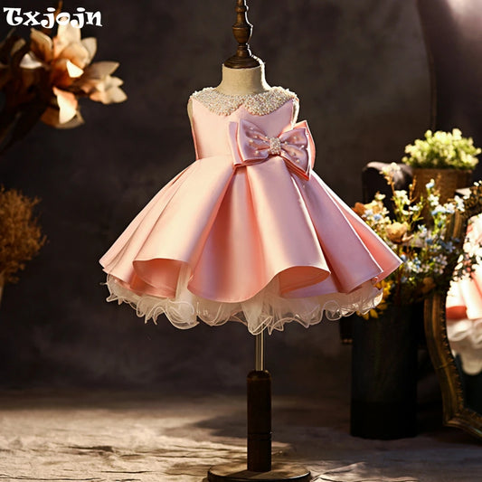 Pink satin princess gown for girls featuring glitter pearls and a bow, ideal for school performances and catwalk shows by Ansoff.