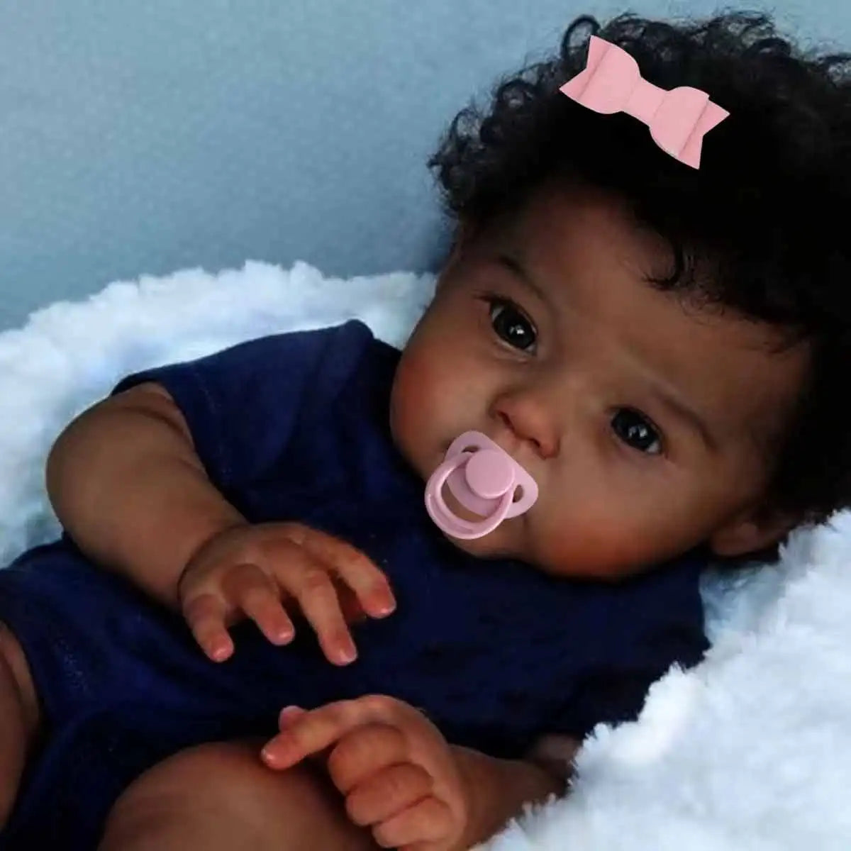 Black Reborn baby doll with soft cloth body, curly hair, realistic features, designed for lifelike play and cuddling.