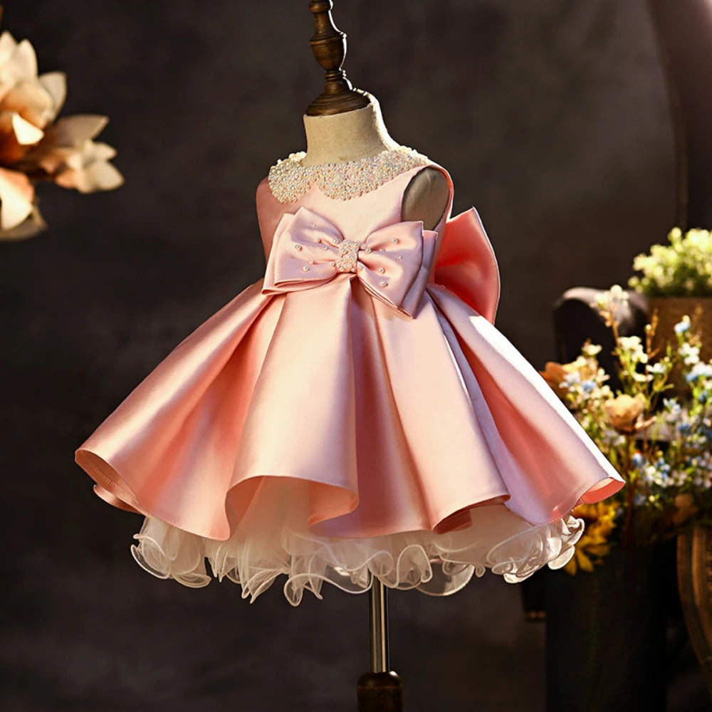 Pink satin girl’s princess gown with glitter pearls, sleeveless design, large bow, perfect for school performances and catwalk shows.